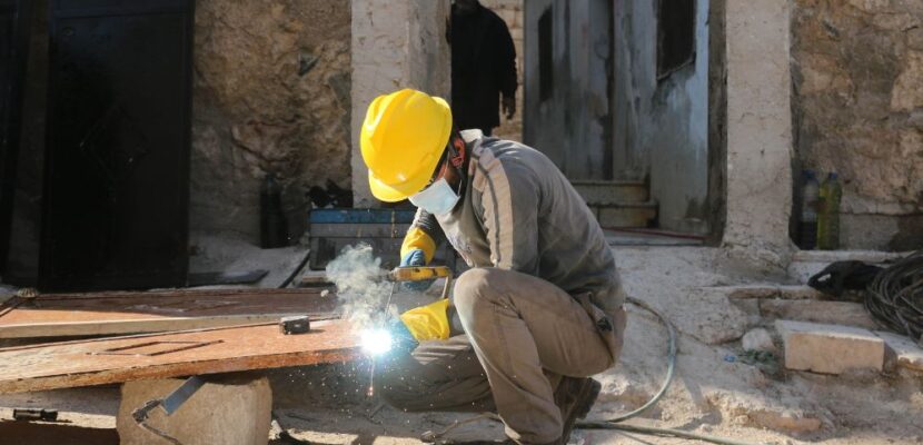 Worker performing welding on metal